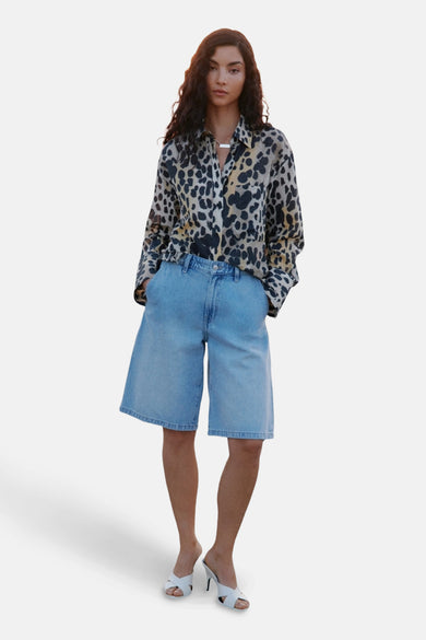 Multikleurig hemd met lange mouwen van MANGO, met een dierenprint en gedragen met denim bermuda shorts en witte hakken.