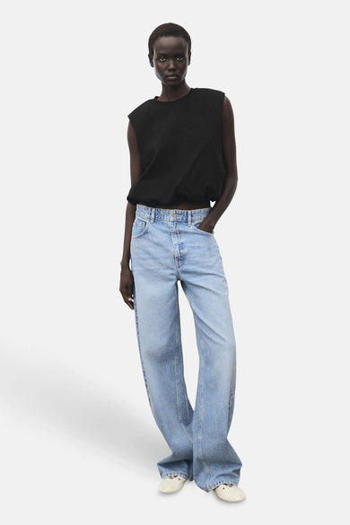 T-shirt noir sans manches de MANGO, avec des jeans bleus délavés et des chaussures écru.