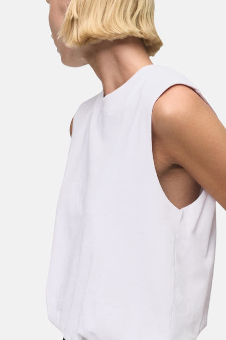 Witte top zonder mouwen van MANGO, zijwaarts gezien met een eenvoudige, effen stijl.
