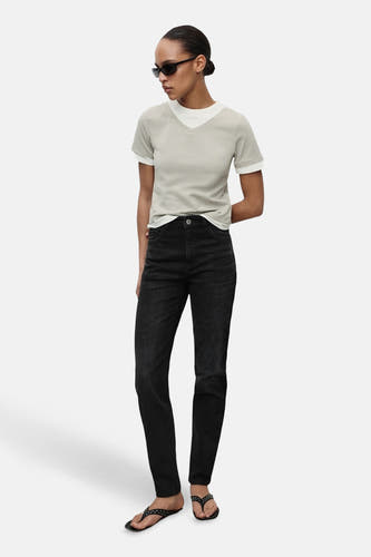Donkergrijze mom jeans van MANGO, gecombineerd met een lichtgrijs T-shirt en zwarte sandalen met studs.
