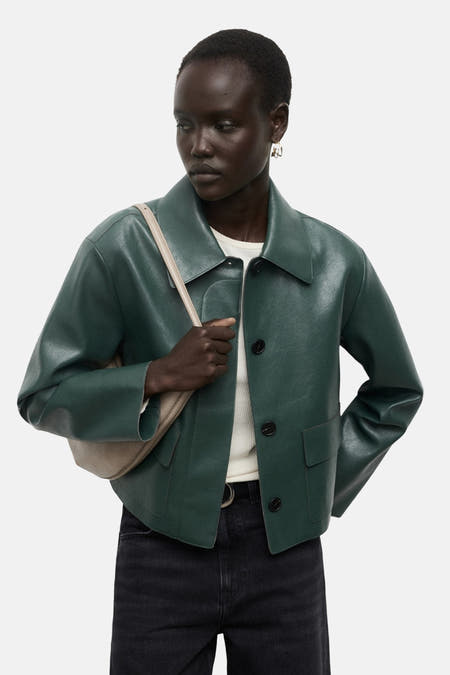 Groene korte jas van MANGO, met knoopsluiting, gedragen over een witte top en een zwarte broek.
