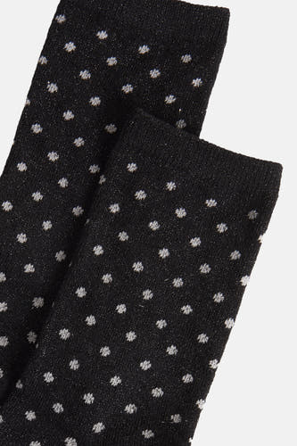 Zwarte sokken van PIECES® met glanzende stippen tegen een effen achtergrond, close-up.
