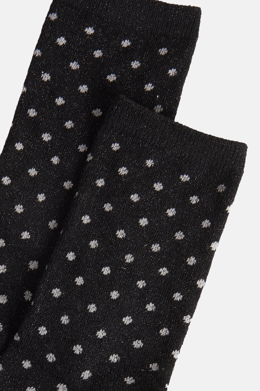 Zwarte sokken van PIECES® met glanzende stippen tegen een effen achtergrond, close-up.
