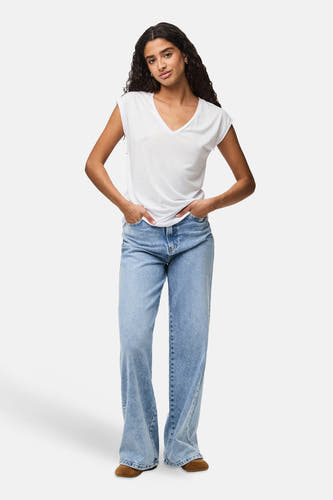 Wit T-shirt met korte mouwen van PIECES®, gedragen met wijde jeans en bruine schoenen.