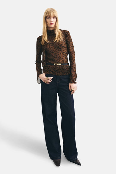 Bruine blouse met lange mouwen van MANGO, met dierenprint, gecombineerd met wijde donkere jeans, gouden ringen en een zwarte riem.

