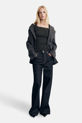 T-shirt gris à manches longues de MANGO, avec une encolure carrée, porté sous un blouson gris et des jeans foncés.