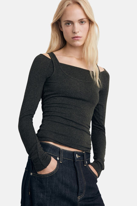 Grijze T-shirt met lange mouwen van MANGO, met vierkante halslijn en donkere denim broek.
