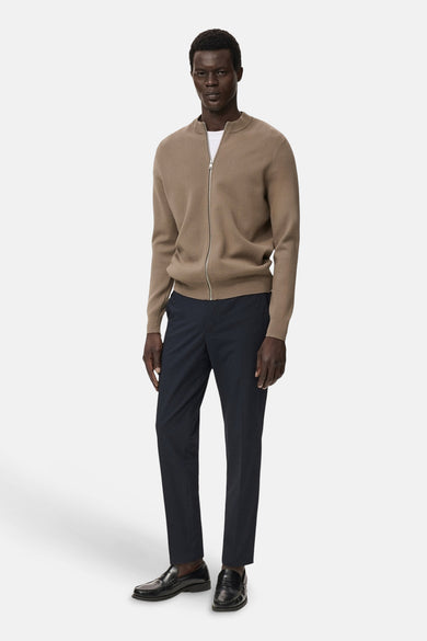 Bruin gilet van MANGO, gedragen over een wit shirt met donkere pantalon en zwarte loafers.
