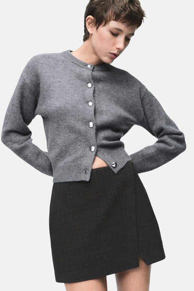 Grijs gilet van MANGO met zilveren knopen, gecombineerd met een geruite minirok.
