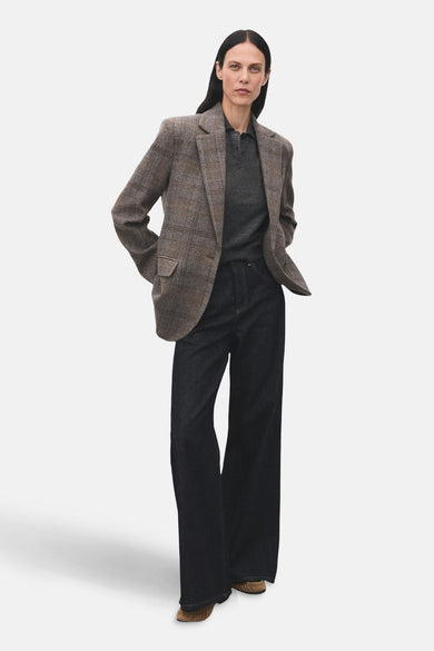 Bruine blazer van MANGO, met ruitpatroon, gecombineerd met een grijze polo en wijde, donkere jeans.