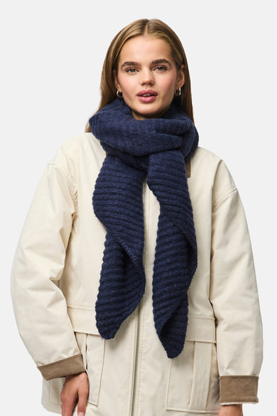 Blauwe wintersjaal van PIECES®, gedragen met een beige jas met rits en manchetten.
