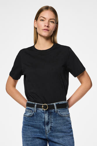 Ceinture noire de PIECES, avec une boucle ronde dorée frappante, portée sur un jean bleu.