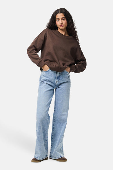 Bruine sweater met ronde hals van PIECES®, gecombineerd met wijde jeans en bruine schoenen.