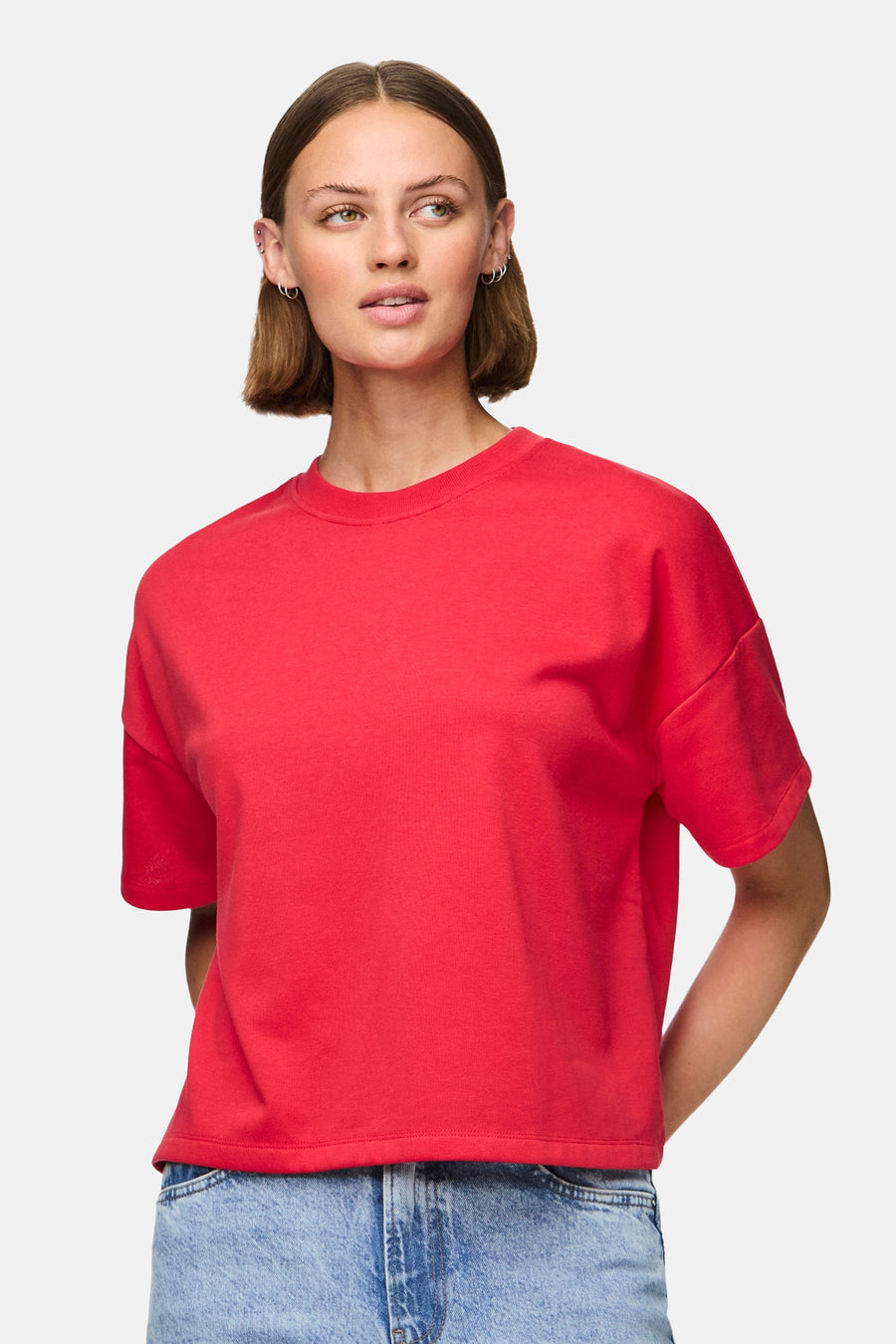 Rood T-shirt met korte mouwen van PIECES®, gedragen met een blauwe jeans.