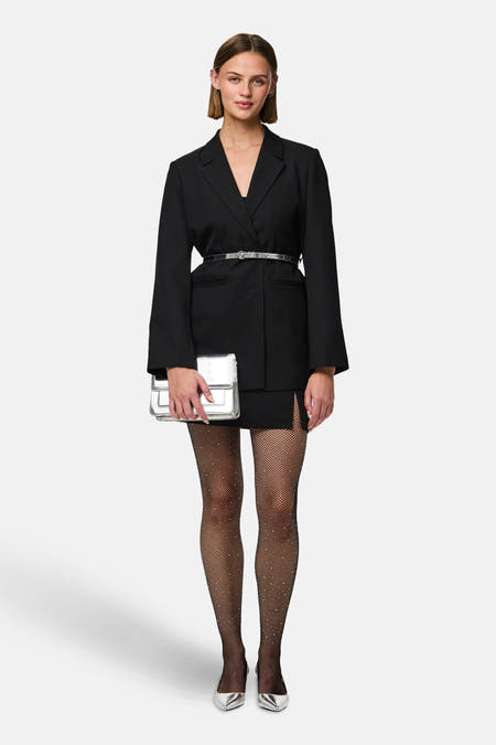Zwarte panty's van PIECES®, met visnetpatroon en subtiele glitterdetails, gedragen met een zwarte blazer en zilveren accessoires.
