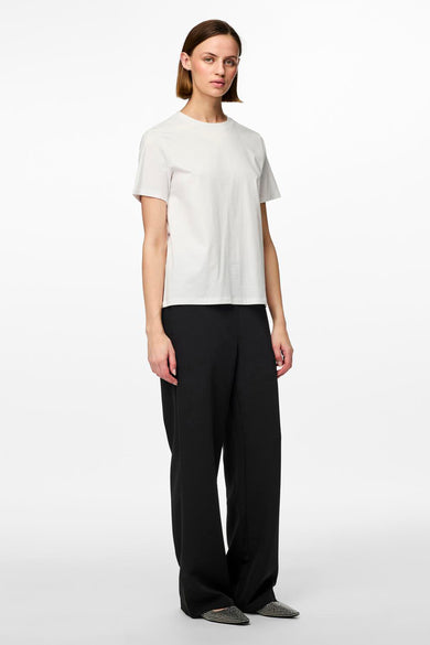 Zwarte joggingbroek van PIECES®, gecombineerd met een wit T-shirt en platte schoenen met studs.