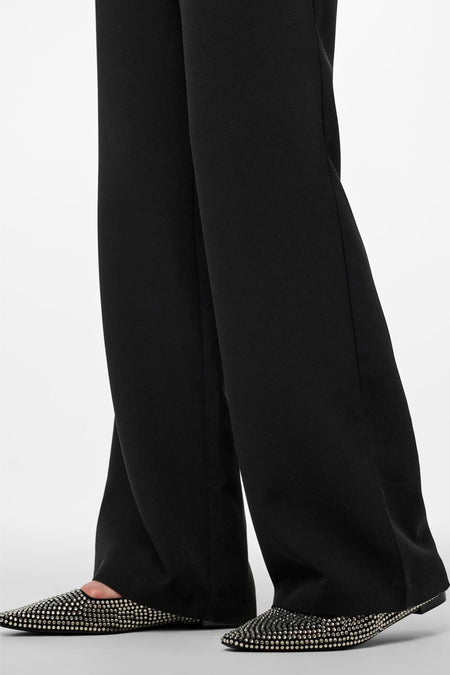 Zwarte joggingbroek van PIECES® met wijde pijpen en zwarte, bezette schoenen.
