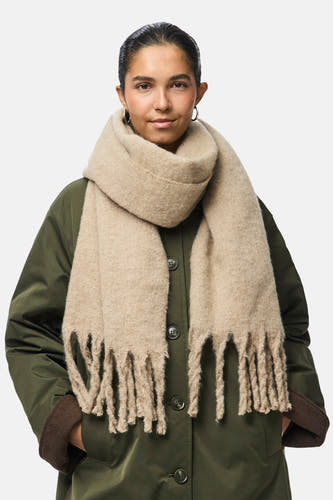 Beige wintersjaal van PIECES®, met grove franjes en gedragen met een olijfgroene jas.