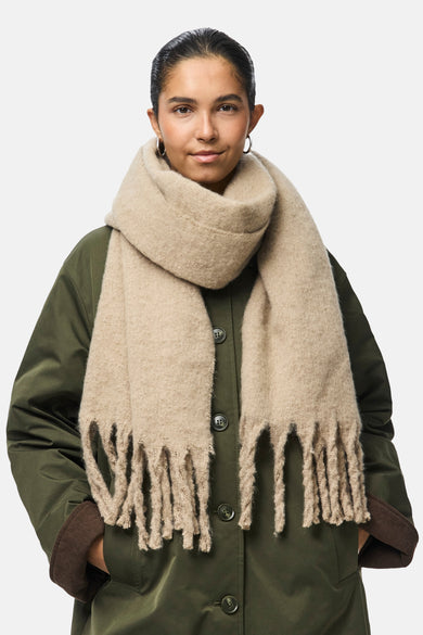 Beige wintersjaal van PIECES®, met grove franjes en gedragen met een olijfgroene jas.