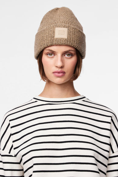 Femme avec un chapeau beige et une chemise rayée.
