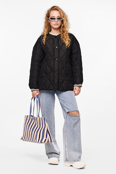 Zwarte korte jas van PIECES®, met ruitjespatroon, gedragen met een blauw gestreepte tas en gescheurde jeans.
