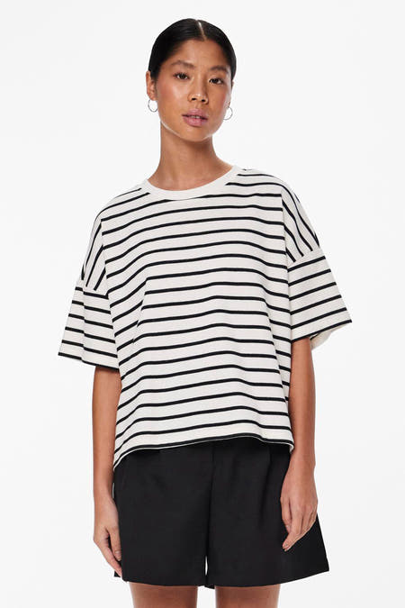 Wit T-shirt met korte mouwen van PIECES® met een zwart gestreept patroon, gedragen met een zwarte short.
