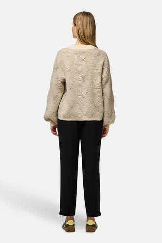 Beige trui met ronde hals van PIECES®, met een gebreid patroon, gecombineerd met een zwarte broek en bruine schoenen.
