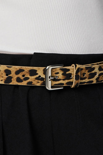 Leopardprint riem met zilveren gesp, zwarte broek, wit shirt.

