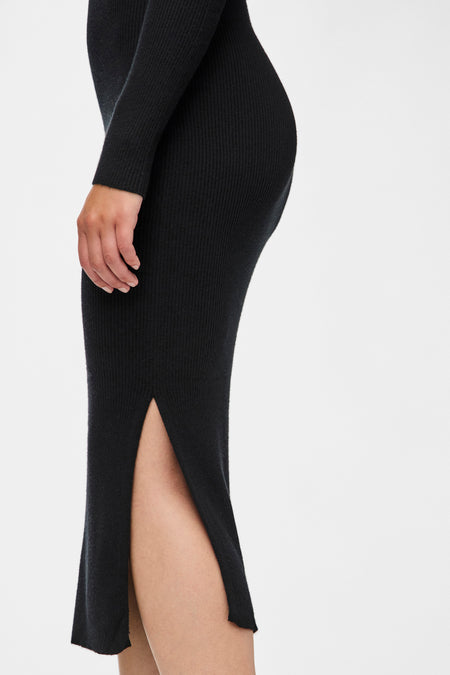Zwarte jurk met lange mouwen van PIECES®, met ribbeltextuur en een hoge split, zij-aanzicht.