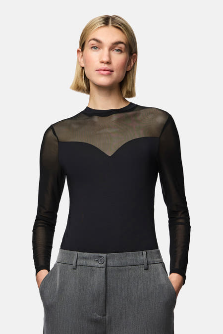 Zwarte body van PIECES®, met lange transparante mouwen en grijze pantalon.
