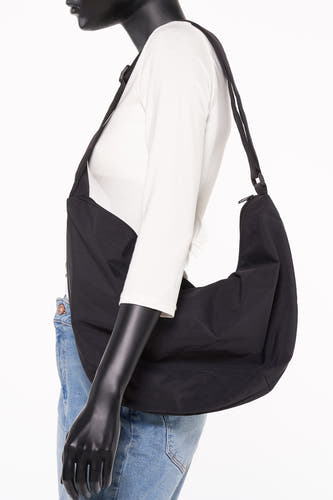 Sac à dos noir de PIECES®, porté sur un t-shirt blanc et un jean, vue de côté.