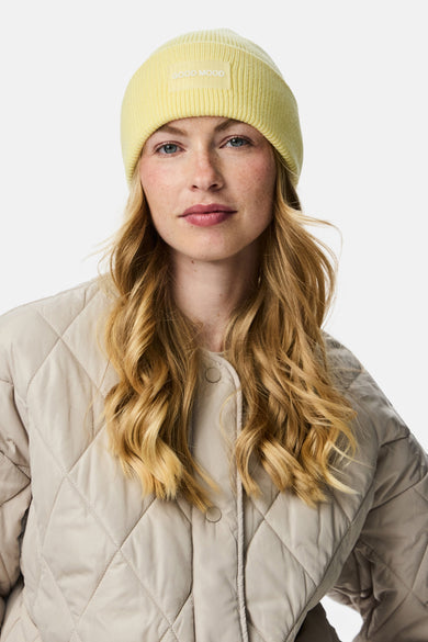 Chapeau marron de PIECES®, avec un patch "Good Mood" et porté avec une veste grattée beige.