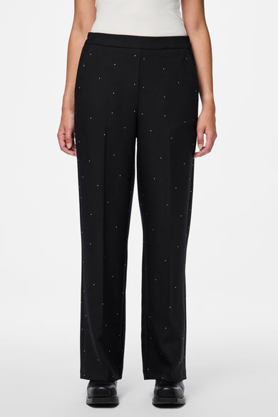 Zwarte broek van PIECES® met kleine stippen, recht model en zwarte schoenen.
