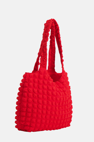 Sac à main rouge de PIECES®, avec une texture en bulles distinctive et des anses doubles.