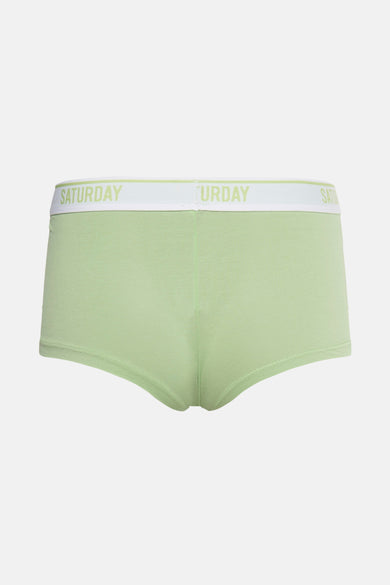 Groene shorty van PIECES® met witte tailleband waarop "SATURDAY" staat afgebeeld.