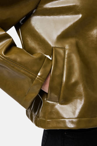 Veste verte de PIECES, avec un fini brillant et une main dans la poche.