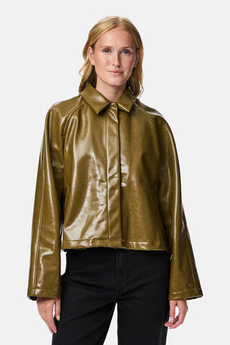 Veste courte verte de PIECES, avec des manches longues et portée sur un pantalon noir.