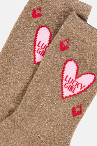 Glimmende beige gebreide sokken van PIECES® met rode hartjes en de tekst 'LUCKY GIRL'.