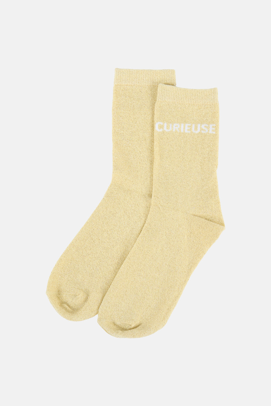 Chaussettes tricotées jaunes de PIECES avec paillettes, le texte 'CURIEUSE' et une étiquette blanche.