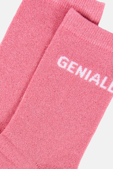 Roze sokken van PIECES® met zilveren glitter en deels zichtbaar opschrift GENIAL.