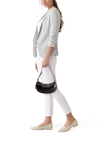 Sac à bandoulière noir de PIECES®, avec texture brillante, porté par un mannequin en pantalon blanc et blazer gris.