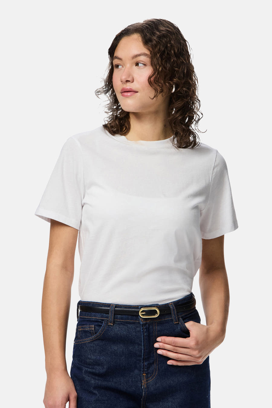 Multicolor riem van PIECES® met een gouden gesp en een donkerblauwe jeans met een witte T-shirt.