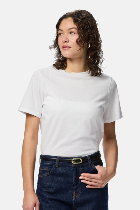 Multicolor riem van PIECES® met een gouden gesp en een donkerblauwe jeans met een witte T-shirt.