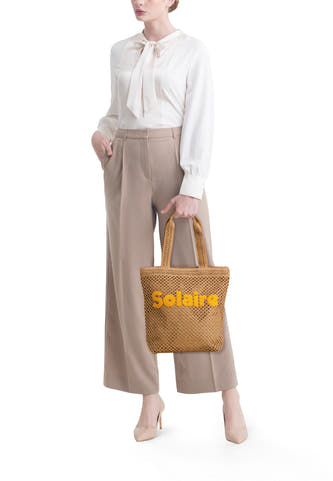 Sac à main tissé marron de PIECES® avec 'Solaire' en lettres jaunes, porté par un mannequin.