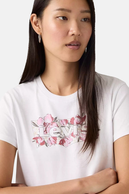 Portret van een vrouw met een wit T-shirt met een bloemmotief van het merk Levi's.