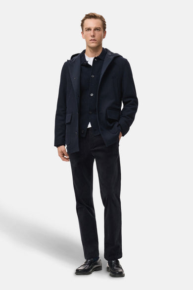 Korte donkerblauwe jas van MANGO, met capuchon en opgestikte zakken, gecombineerd met corduroy pantalon en leren loafers.
