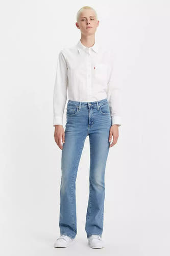 Jean bootcut bleu clair de Levi's, porté avec un chemisier blanc et des baskets blanches, en vue latérale.
