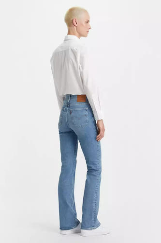 Jean bootcut bleu clair de Levi's, avec un chemisier blanc et des baskets blanches.