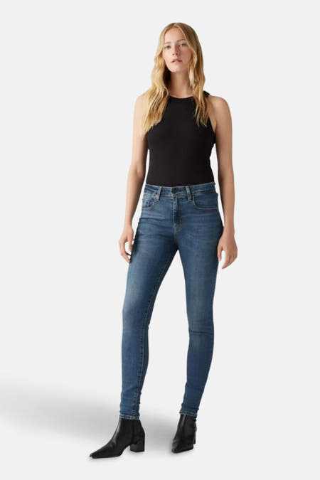 Jean skinny en denim bleu marine de Levi's, vu de l'arrière avec un tanktop noir et des bottines noires.