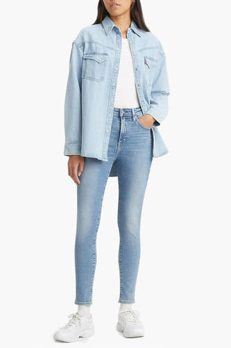 Lichtblauwe denim skinny jeans van Levi's, gecombineerd met een lichtblauw overhemd en witte sneakers.